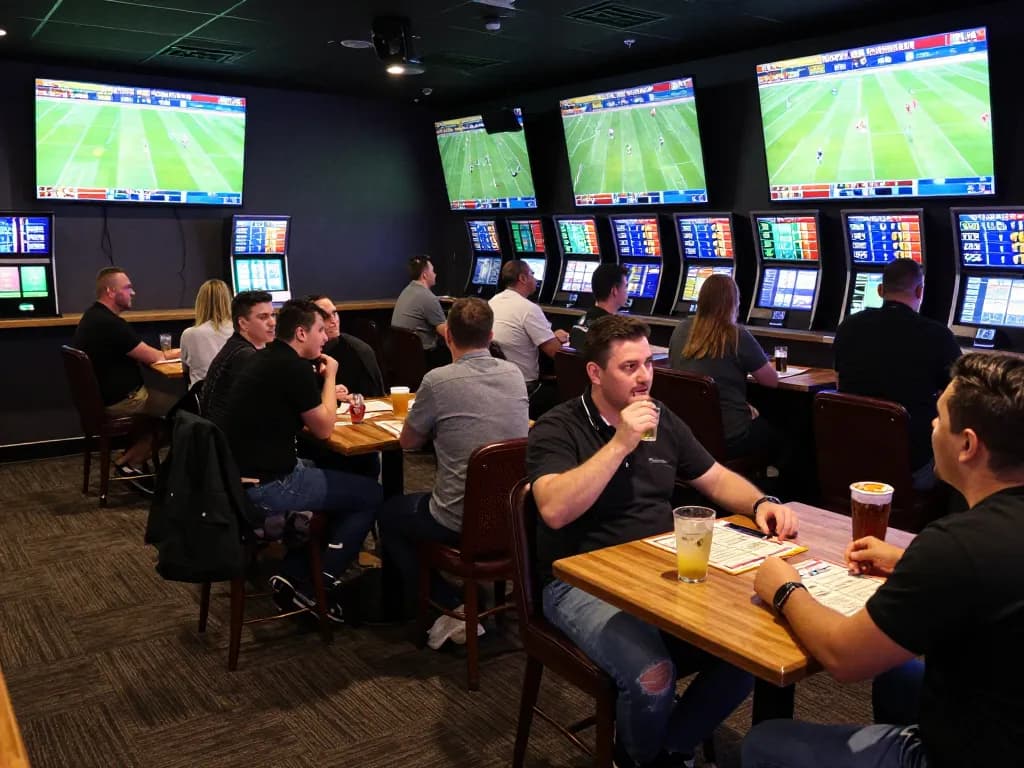 Engaged bettors analyzing tỷ lệ kèo bóng đá trực tuyến while watching live football matches on digital screens